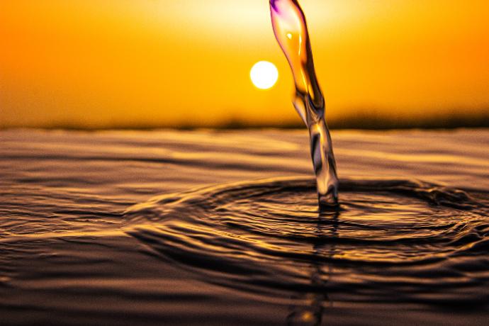 water drop on brown sand during sunset